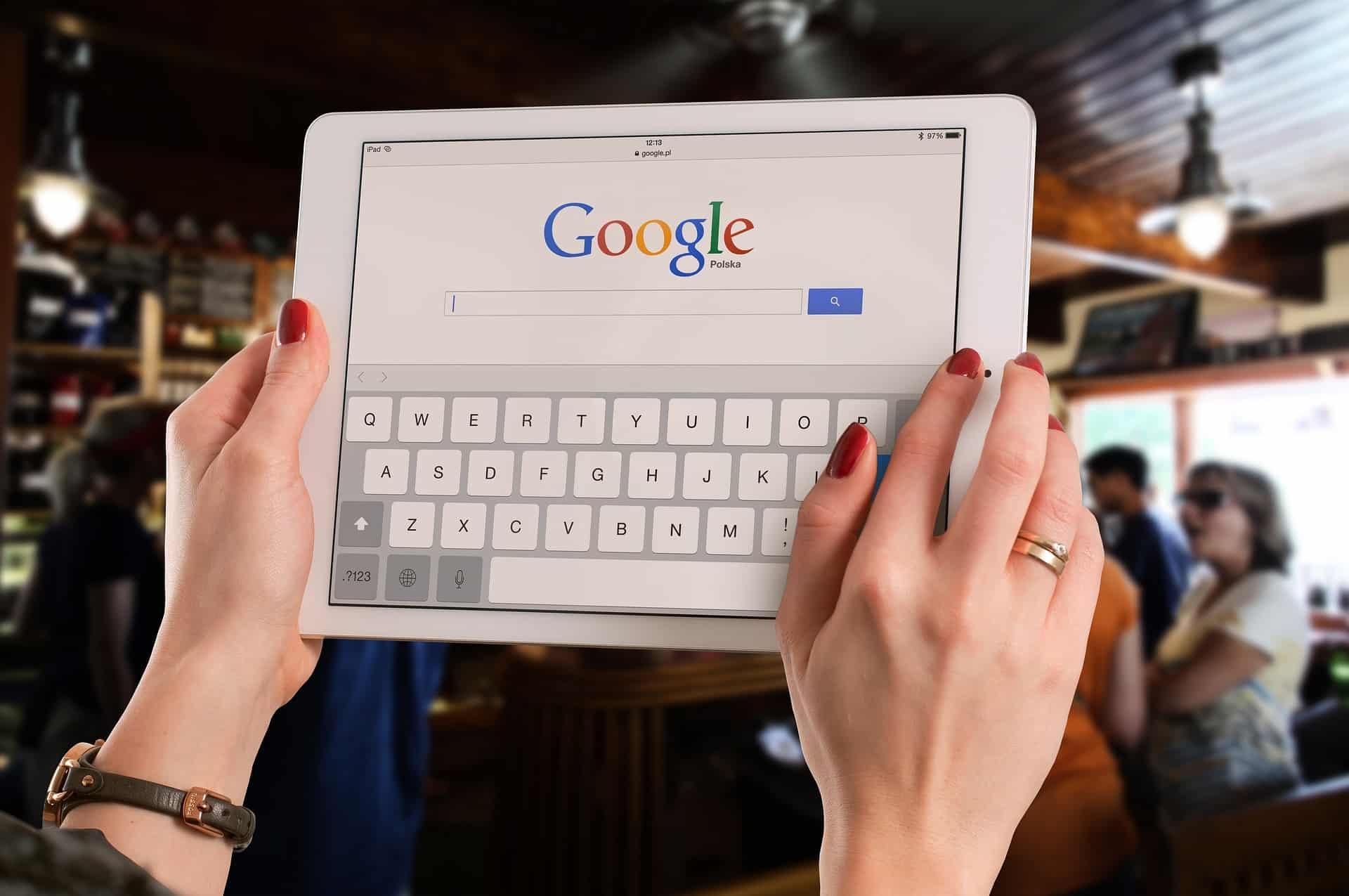 Eine Frau hält ein iPad hoch mit Google-Suchfeld auf dem Startbildschirm. Das Bild steht symbolisch für SEO und SEA als Online-Marketingmaßnahmen.