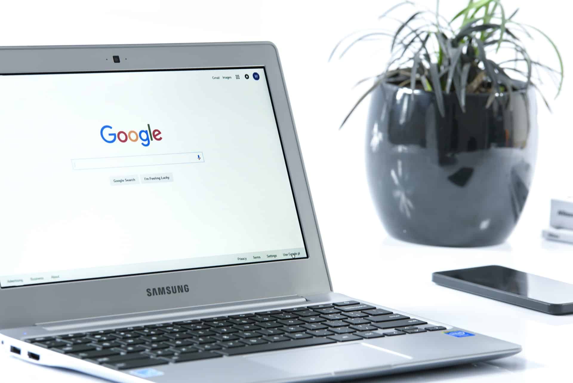 A laptop on the desk - the opened screen shows a Google search box. Example of SEO keyword research.