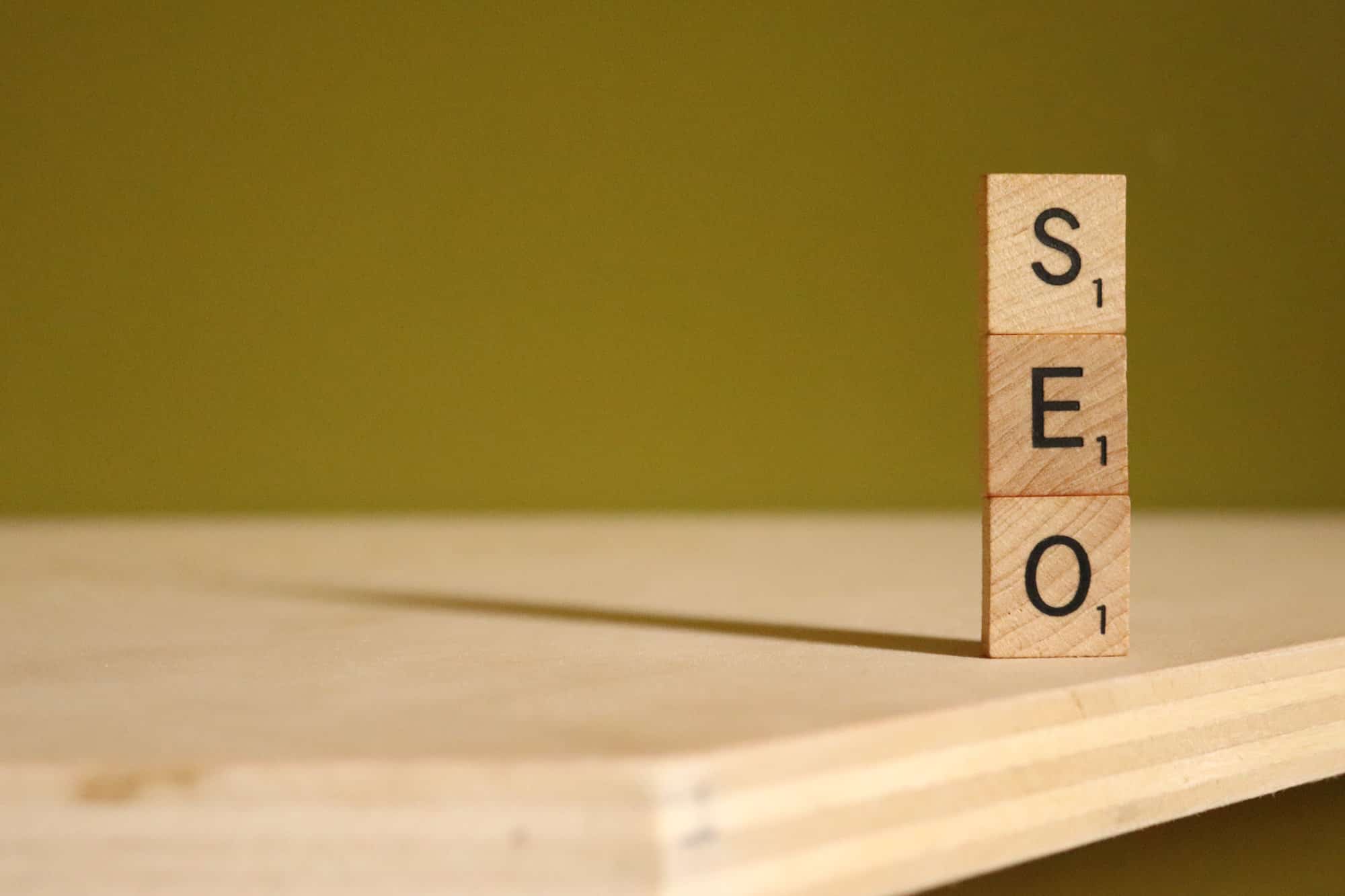 Scrabble-Spielsteine mit den Buchstaben SEO sind auf einem Tisch gestapelt - als Symbol für ein SEO Ranking