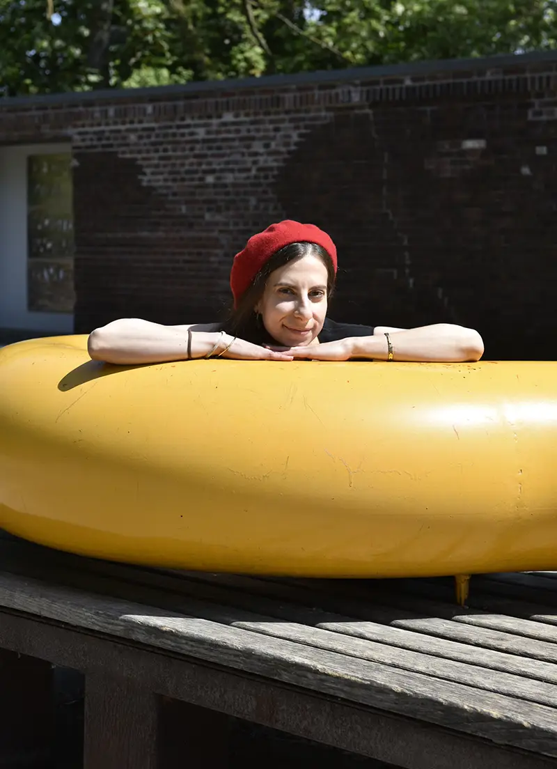 Designerin Giulia Cappello lehnt sich auf eine abstrakte gelbe Skulptur