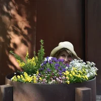 Web editor Manuela Nagel looks out from behind a flowerpot