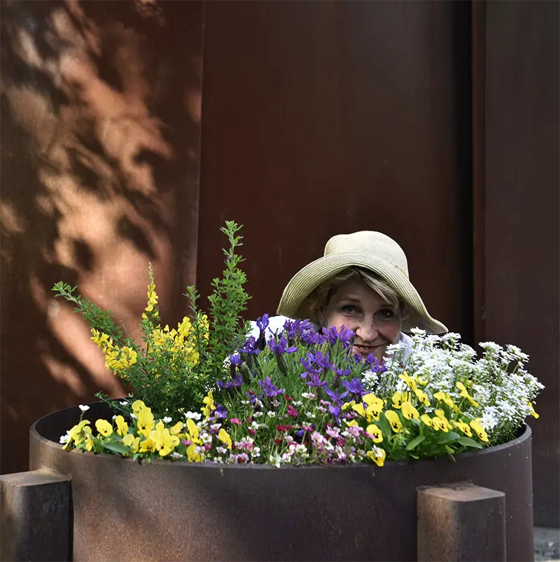 Web editor Manuela Nagel looks out from behind a flowerpot